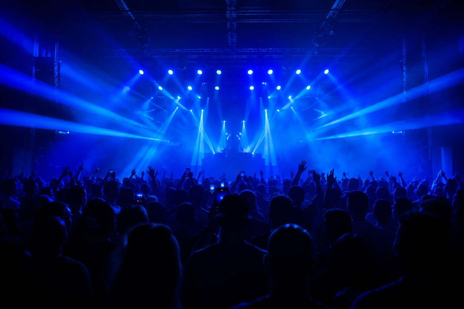 Palco iluminado visto do fundo da pista, com o público de costas
